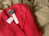 a red sweater and khaki pants sitting on a bed