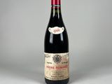 une vieille bouteille de vin posée sur une table blanche