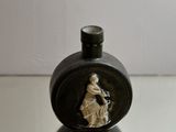 a small black vase with a picture of a woman on it