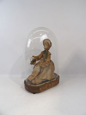 une figurine représentant une femme assise sous une cloche de verre