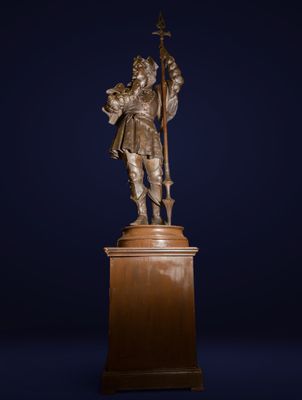 une statue en bronze représentant un homme tenant une croix, posée sur un socle