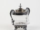 an antique silver and glass teapot with a lid on a stand