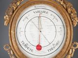 a gold clock with a barometer in the middle of it