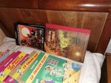 Plusieurs livres pour enfants sont posés sur un lit recouvert d'une couverture blanche.