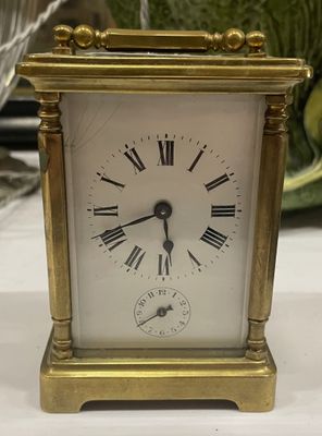 une petite horloge en or avec des chiffres romains
