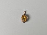 un petit pendentif orné d'une pierre jaune sur un fond blanc