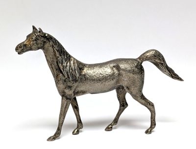 une statue en argent représentant un cheval sur fond blanc