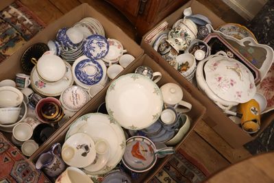 deux cartons remplis de vaisselle en porcelaine et de bols, posés par terre