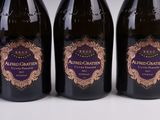 trois bouteilles de vin sont alignées sur une surface blanche