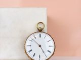 an old pocket watch sitting on a marble block next to a pink wall