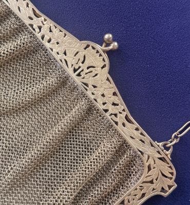 a close up of a silver purse on a blue surface