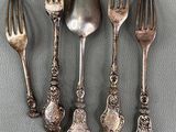 four silver spoons and a fork on a gray surface