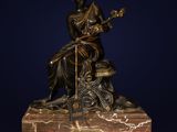 une statue en bronze représentant une femme assise sur un rocher