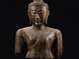une statue en bois représentant un Bouddha sur fond noir
