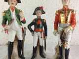 three figurines of men dressed in military uniforms