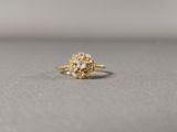 un gros plan d'une bague sertie d'un diamant jaune posée sur une surface grise