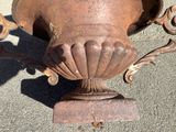 a rusted urn sitting on a cement surface