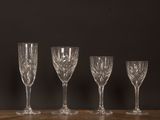 four empty wine glasses lined up on a wooden table