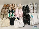 many pairs of shoes and clothes laid out on a table