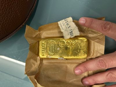 a person holding a piece of gold on top of a piece of paper