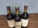 three bottles of wine sitting on top of a wooden table