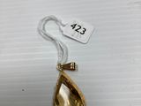 a gold necklace with a tear shaped pendant hanging from it ' s side