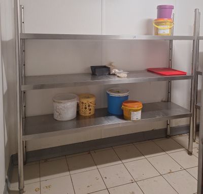 une étagère métallique sur laquelle sont posés des seaux, dans une cuisine