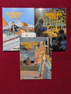 trois livres posés sur un tissu rouge orné de l'image d'une femme sur un bateau