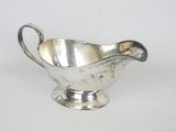 une saucière ancienne en argent, dotée d'un manche incurvé, sur fond blanc