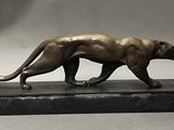statue d'une panthère posée sur un socle en marbre, sur fond gris