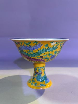 yellow and blue bowl with dragon design on it on a table