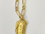a close up of a gold necklace with a jesus head on it