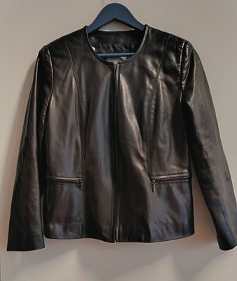 une veste en cuir noir suspendue à un cintre sur un mur blanc