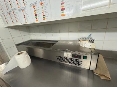 un plan de travail en acier inoxydable dans la cuisine d'un restaurant, avec un rouleau de papier toilette posé dessus