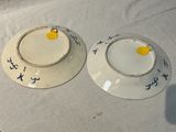 two white plates with blue designs on them sitting on a table