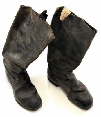 une paire de bottes en cuir noir posée sur une surface blanche