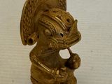 une figurine en or posée sur une surface blanche
