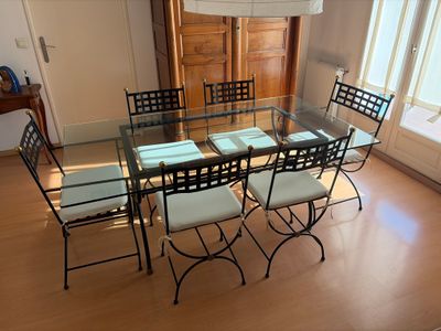 une table et des chaises en verre dans une pièce avec du parquet