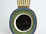 un vase bleu et vert posé sur une surface blanche