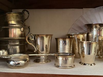 many silver cups and cups sitting on a shelf