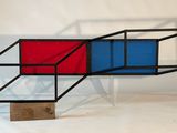 un objet rouge et bleu posé sur un socle en bois