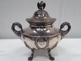 a silver vase with a bird on top of it