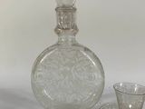 a glass bottle and a glass cup sitting on a table