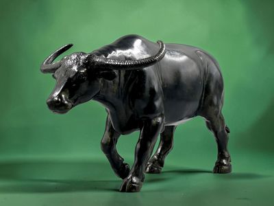 une statue représentant un taureau marchant sur un fond vert