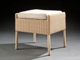 un tabouret en osier rembourré, surmonté d'un coussin