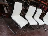 Quatre chaises blanches sont alignées en rang dans un entrepôt