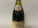 une vieille bouteille de vin posée sur une table blanche