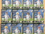Plusieurs boîtes de figurines Playmobil sur le thème du football sont empilées les unes sur les autres