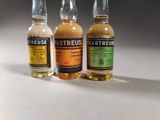 three small bottles of alcohol sitting on top of a white table