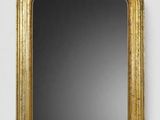 un miroir à cadre doré accroché à un mur blanc sur fond noir